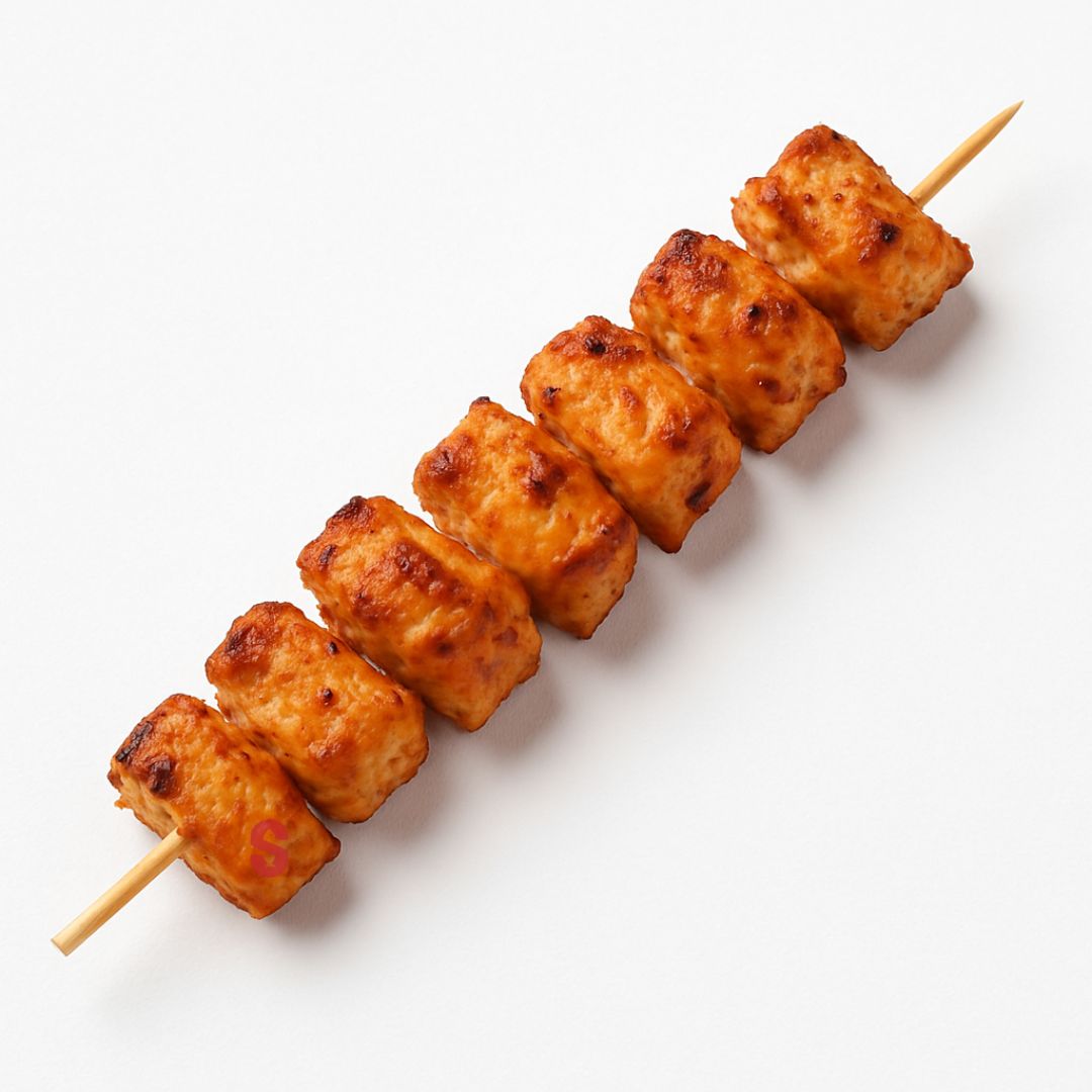 Skewer of golden brown chicken skewers cubes on a white background
