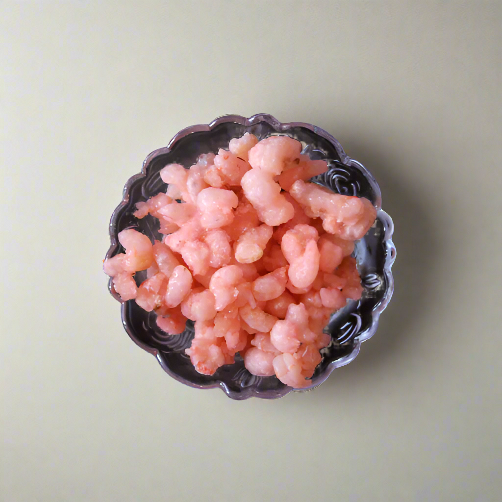A bowl of cooked shrimps on a dark background.
