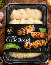 A packaged loaf of Garlic Bread in a clear plastic tray with a black label. The bread is topped with visible garlic cloves and cheese-like pieces.