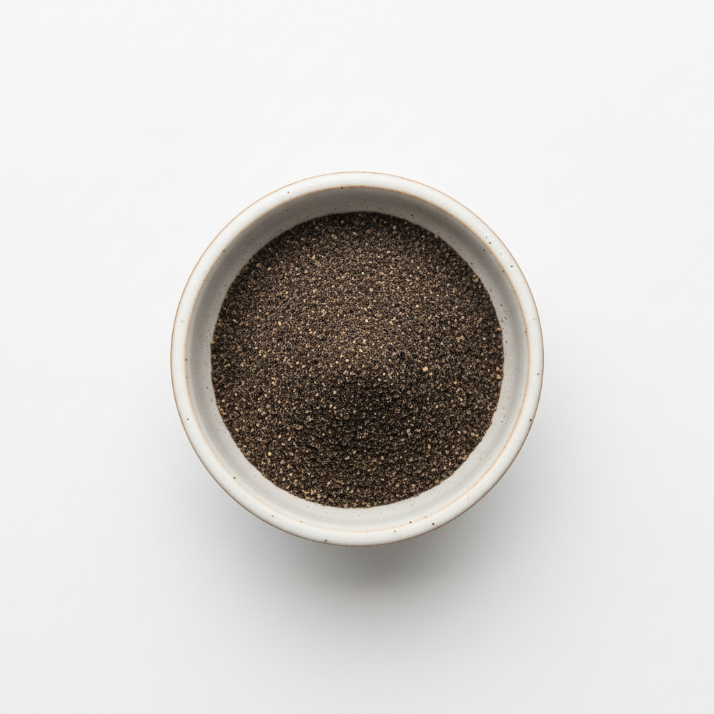 Small bowl filled with dark chia seeds on a light gray background